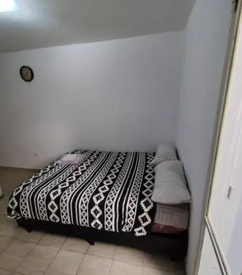a bed with a black and white blanket and pillows at Rondeau Studios Apartaments in Cordoba