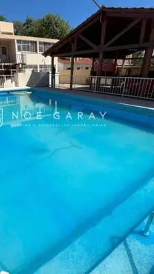 a large blue swimming pool with a building in the background at Santa Rita Dpto in Villa Carlos Paz