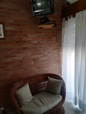 a room with a couch and a tv on a brick wall at Santa Rita Dpto in Villa Carlos Paz