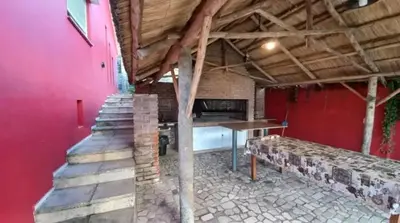 a room with a red wall and a table and stairs at Villa Gesell Diego Sarmiento in Villa Carlos Paz