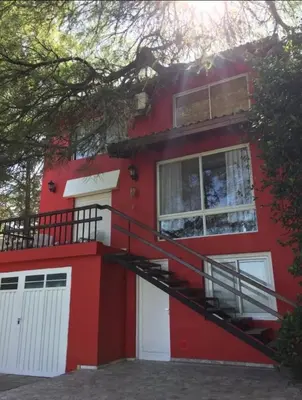 a red house with a staircase in front of it at Villa Gesell Diego Sarmiento in Villa Carlos Paz
