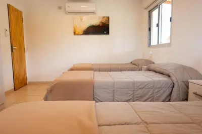 a room with three beds and a painting on the wall at Pipperland Hospedaje in Villa García