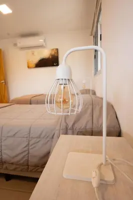 a white lamp on a table next to a bed at Pipperland Hospedaje in Villa García