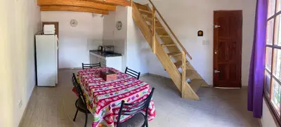 a dining room with a table and a staircase at Cabañas Onírico - Duplex in Mina Clavero
