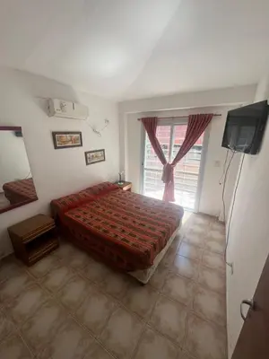 a bedroom with a bed and a large window at Depto para 4 personas con pileta a 3 cuadras del rio in Villa Carlos Paz