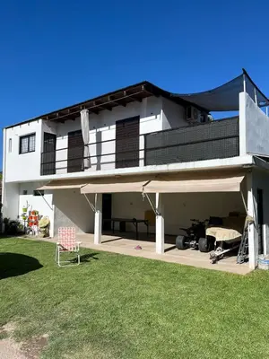 a large white house with a lawn in front of it at Crisol departamento in Alta Gracia