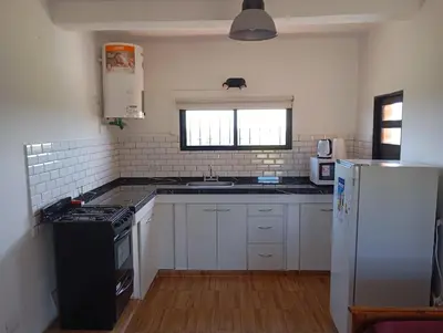 a kitchen with white cabinets and a black refrigerator at Los Espinillos in Villa Yacanto