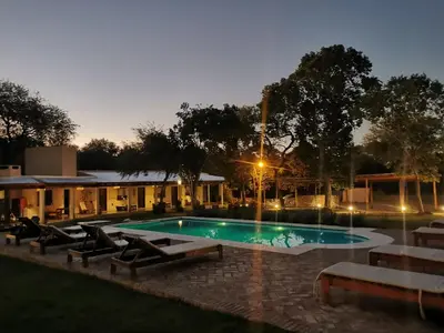 a swimming pool at night with lounge chairs around it at Las Chuncas Posada Chill Villa de las Rosas in Villa de Las Rosas