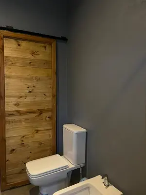 a bathroom with a white toilet and a wooden wall at 