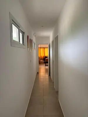 a long hallway with white walls and a window at Complejo playa de oro 3 in Villa Carlos Paz