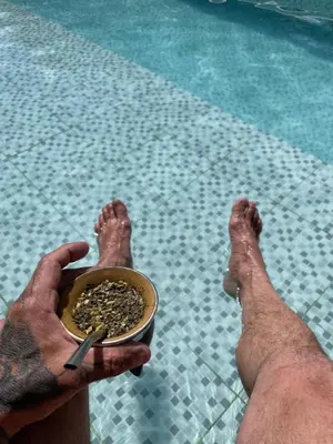 a man holding a bowl of food next to a pool at Cabañas Aaron in Villa de Las Rosas