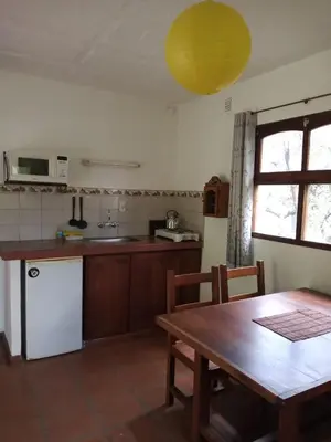 a kitchen with a wooden table and a table and a dining room at Cabañas Aaron in Villa de Las Rosas