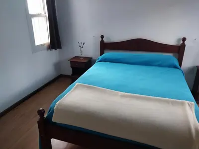 a bedroom with a bed with blue sheets and a window at Big House in Merlo