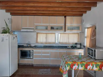 a kitchen with wooden cabinets and a table and a refrigerator at Big House in Merlo