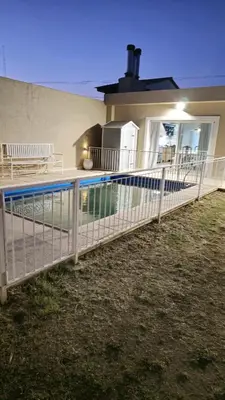 a fence around a swimming pool in front of a house at La Casa De Los Recuerdos in Villa Carlos Paz