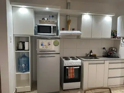 a kitchen with white cabinets and a stove and a microwave at Casa en Tanti con pileta in Tanti
