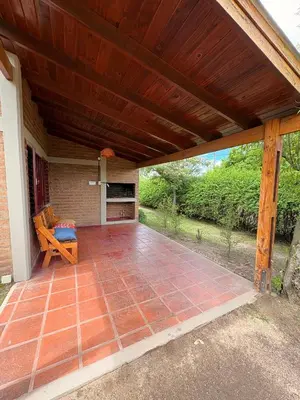 an outdoor patio with a wooden roof and a bench at Sierra Dulce in Mina Clavero