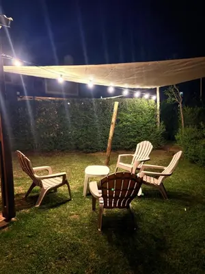 three chairs and a table in a yard at night at Sierra Dulce in Mina Clavero