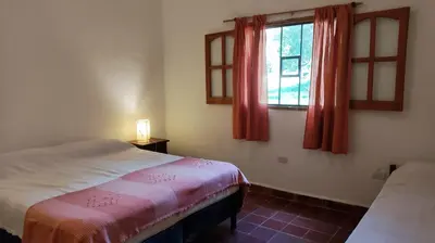 a bedroom with a bed and a window with red curtains at Don Juan M Cabañas in Villa de Las Rosas
