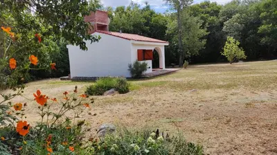 a small white building with a red door in a field at Don Juan M Cabañas in Villa de Las Rosas