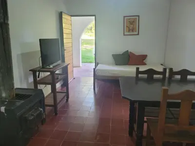 a living room with a bed and a table and a tv at Don Juan M Cabañas in Villa de Las Rosas
