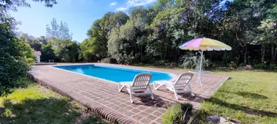 two chairs and an umbrella next to a swimming pool at Don Juan M Cabañas in Villa de Las Rosas