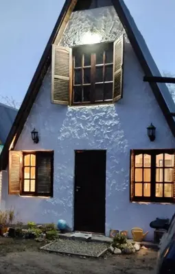 a white house with windows and a door at Alpinas El Chusmo in Villa Ciudad Parque