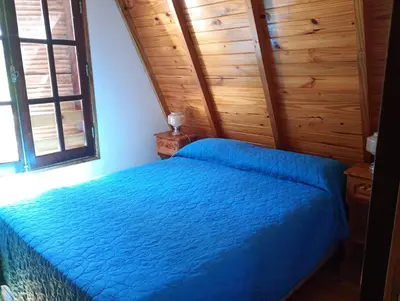 a bedroom with a blue bed in a room with wooden walls at Alpinas El Chusmo in Villa Ciudad Parque