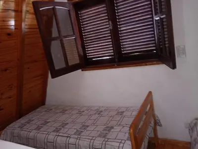 a small bedroom with a bed and a window at Alpinas El Chusmo in Villa Ciudad Parque