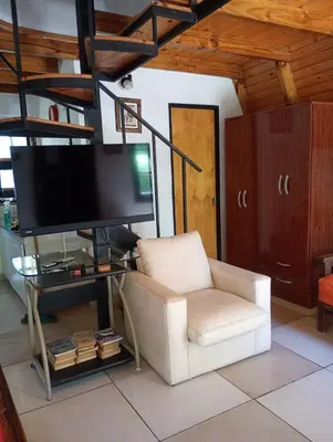 a living room with a white chair and a flat screen tv at Alpinas El Chusmo in Villa Ciudad Parque