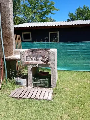 a stone fireplace in the grass in front of a house at Alpinas El Chusmo in Villa Ciudad Parque