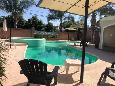 a swimming pool with chairs and an umbrella at Chalet Los Aromos in Embalse