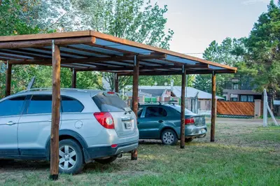 two cars parked under a wooden pavilion at Complejo Montana in Potrero de Garay
