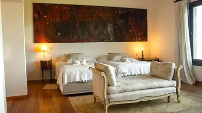 a bedroom with two beds and a chair and a painting at Merlín Art Lodge in Atos Pampa