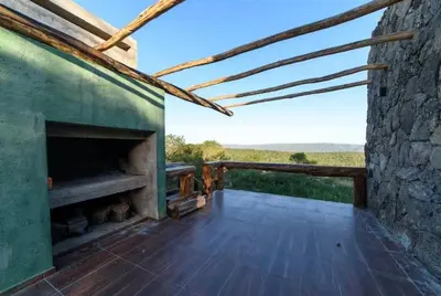 an outdoor deck with a fireplace and a stone wall at Merlín Art Lodge in Atos Pampa