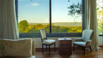 a living room with two chairs and a large window at Merlín Art Lodge in Atos Pampa