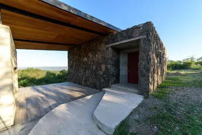 a stone building with a door and a stone wall at Merlín Art Lodge in Atos Pampa