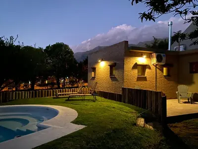 a house with a table and a bench in the yard at Shamrock House - Casa de Vacaciones en Merlo, San Luis in Merlo