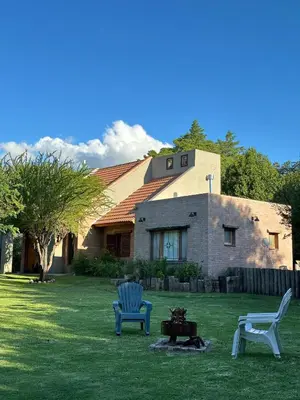 two chairs and a table in front of a house at Shamrock House - Casa de Vacaciones en Merlo, San Luis in Merlo