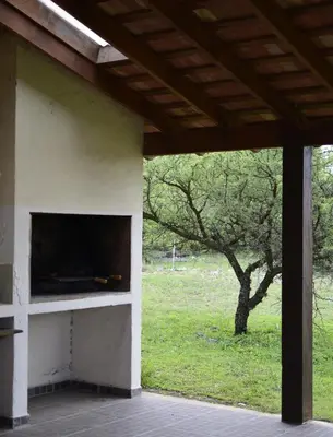 a building with a fireplace with a tree in a field at Las Calandrias in Los Reartes