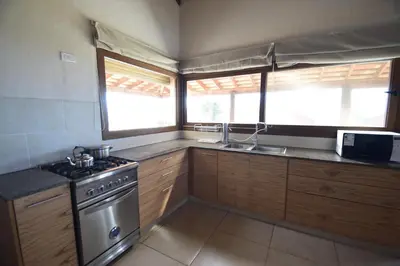 a kitchen with a stove and a sink and windows at Las Calandrias in Los Reartes