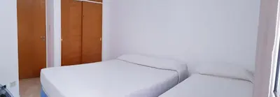 a white bed in a room with a door at Alojamiento Centro de Carlos Paz in Villa Carlos Paz