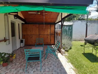 a patio with two chairs and a green umbrella at La Quinta in Villa Carlos Paz