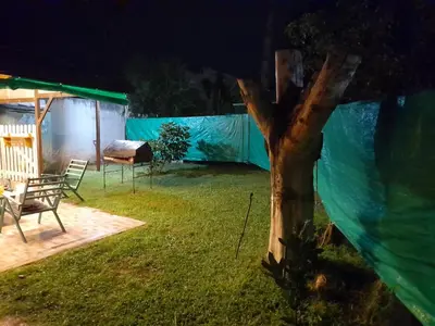 a backyard at night with a fence and a tree at La Quinta in Villa Carlos Paz