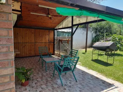 a patio with chairs and a table and a grill at La Quinta in Villa Carlos Paz