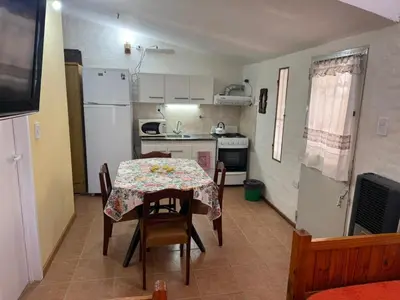 a kitchen with a table and chairs and a kitchen with a refrigerator at La Quinta in Villa Carlos Paz
