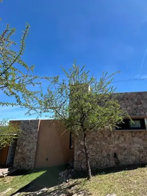 a stone building with a tree in front of it at Refugio de las Nubes in Las Rabonas