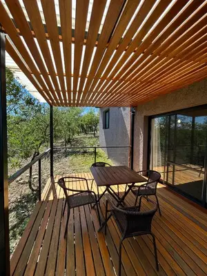 a wooden deck with a table and chairs on it at Refugio de las Nubes in Las Rabonas