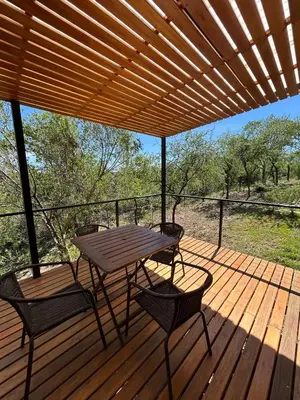 a wooden deck with a picnic table and chairs on it at Refugio de las Nubes in Las Rabonas