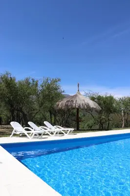 a group of chairs and an umbrella next to a swimming pool at Refugio de las Nubes in Las Rabonas